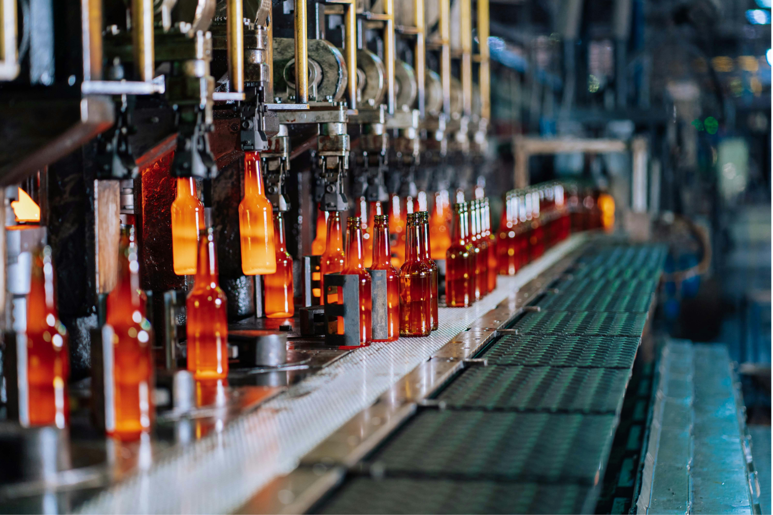 Automated system of conveyers to make bottles. Bottles are glowing from heat from creation